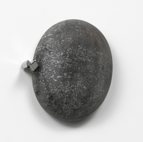 A stand of yellow cherrywood mounted on a wall with a small white, red and aluminum sculpture on top of it