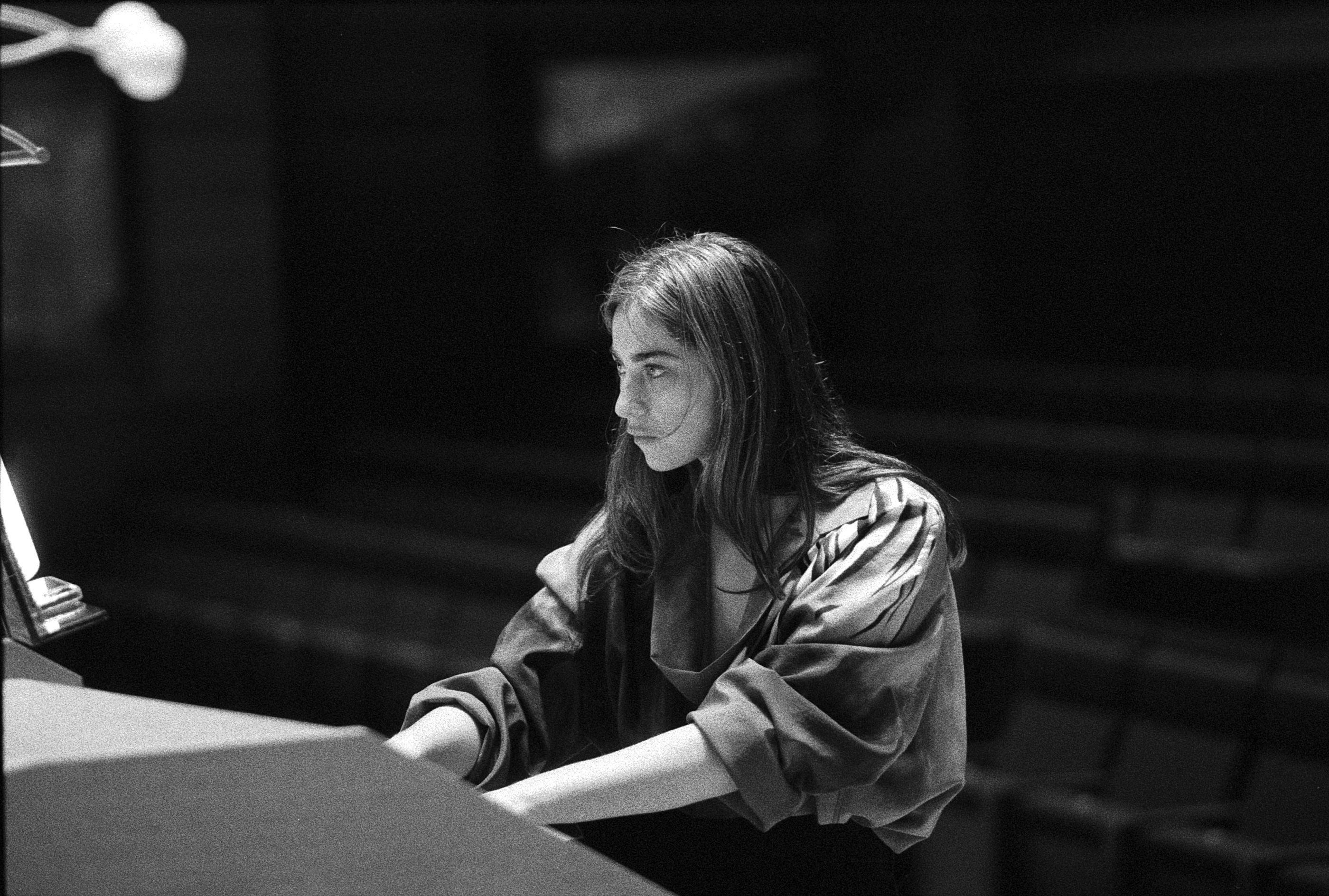 Black and white portrait of woman at organ in dark setting